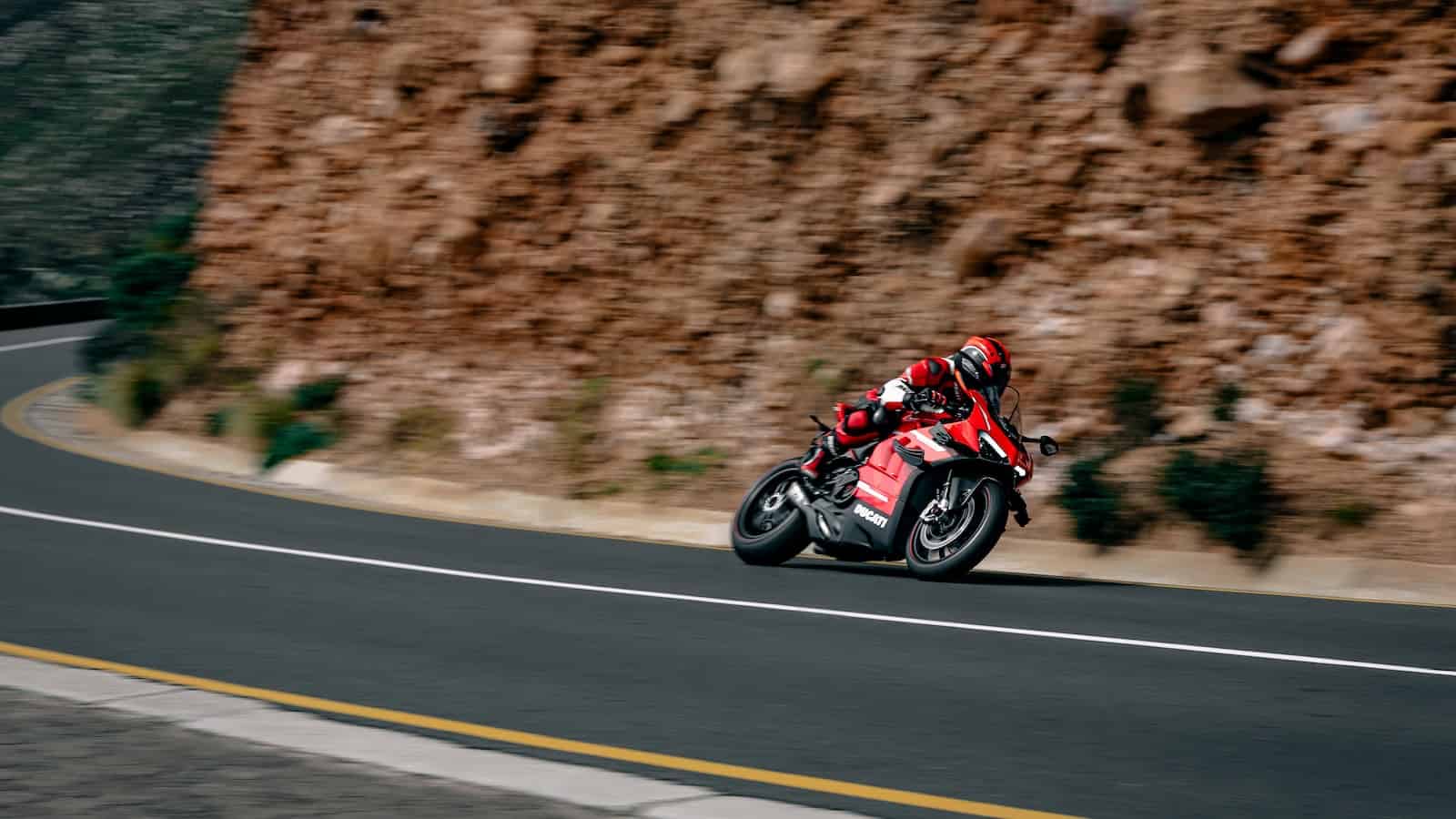 a man riding a red motorcycle down a curvy road